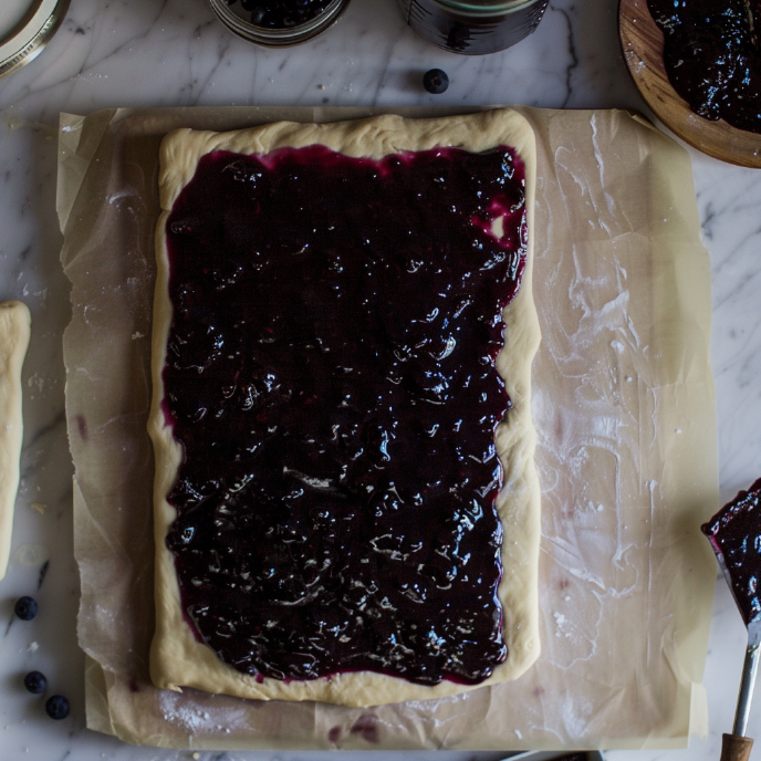 Cinnamon roll dough covered in blueberry jam